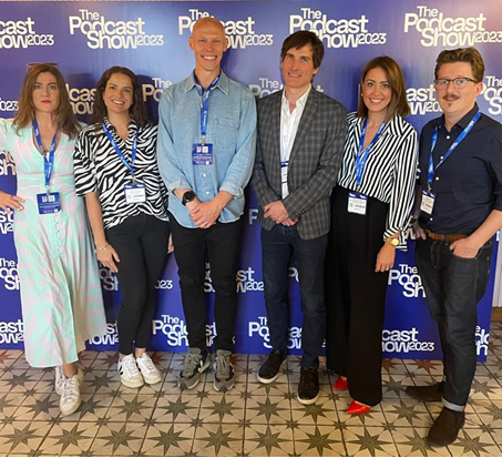 A group of people standing in front of a sign

Description automatically generated