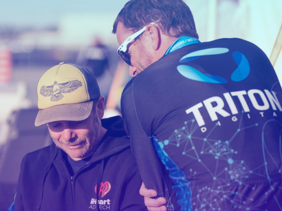 Two men wearing Triton Digital branded clothing